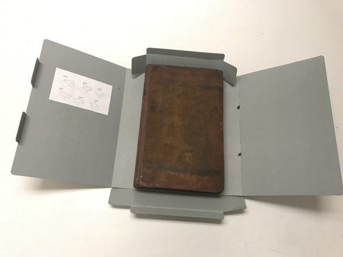 brown leather-bound book inside custom gray box