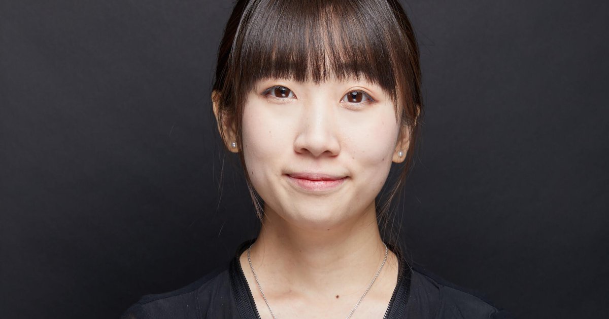 Xinye Zou in black top posing on a black backdrop