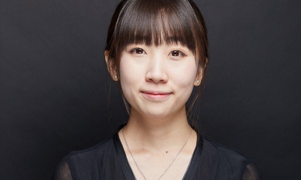 Xinye Zou in black top posing on a black backdrop