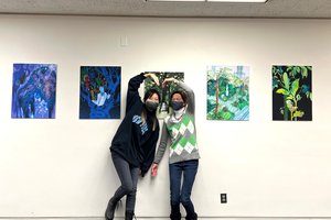 Artist Xuan Liu and Librarian S. Ann Skiold pose in front of artwork on display.