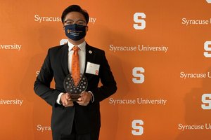 Ze Zing holds an Orange Circle Award plague