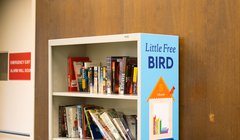 book shelf with sign that reads Little Free Bird with bird house graphic on side