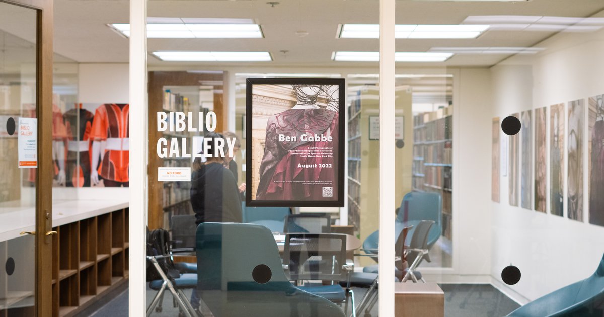looking through glass into room with conference table and artwork on display on the wall