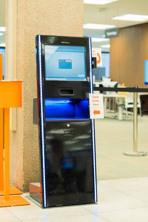 self-standing kiosk with sign that says "stack books here"