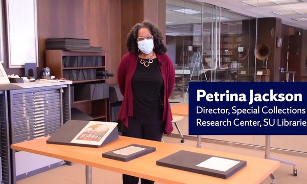 black woman wearing mask standing next to materials from archives