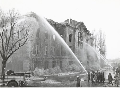 firefighters spraying water at burning Archbold building