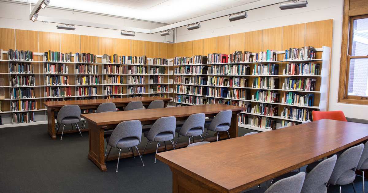 Bookshelves of architecture collections in King + King Architecture Library with long wooden tables and gray fabric chairs