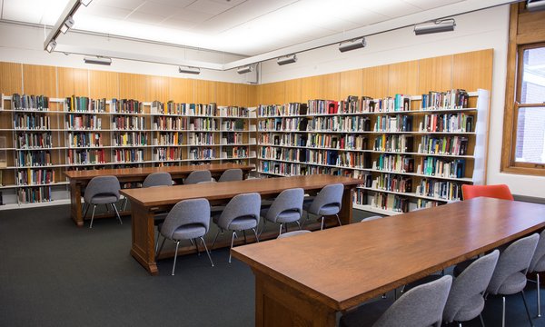 Bookshelves of architecture collections in King + King Architecture Library with long wooden tables and gray fabric chairs