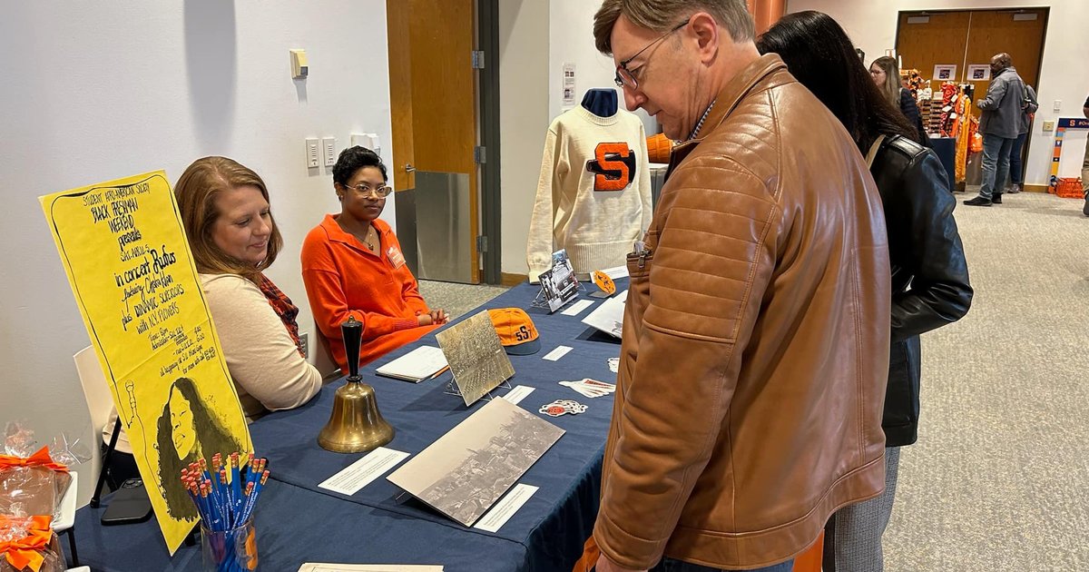 two people sitting at archives table while alumni stop by
