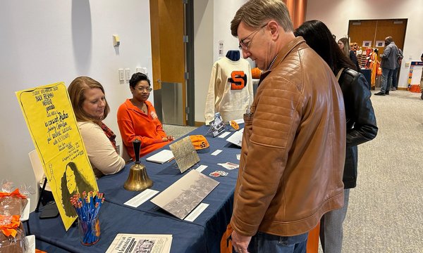 two people sitting at archives table while alumni stop by