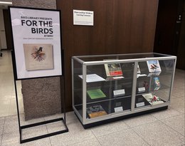 poster that says "For the Birds at Bird" on left next to glass display case