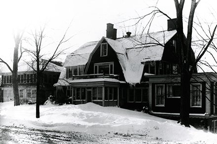 wood colonial house with snow on roof and outside