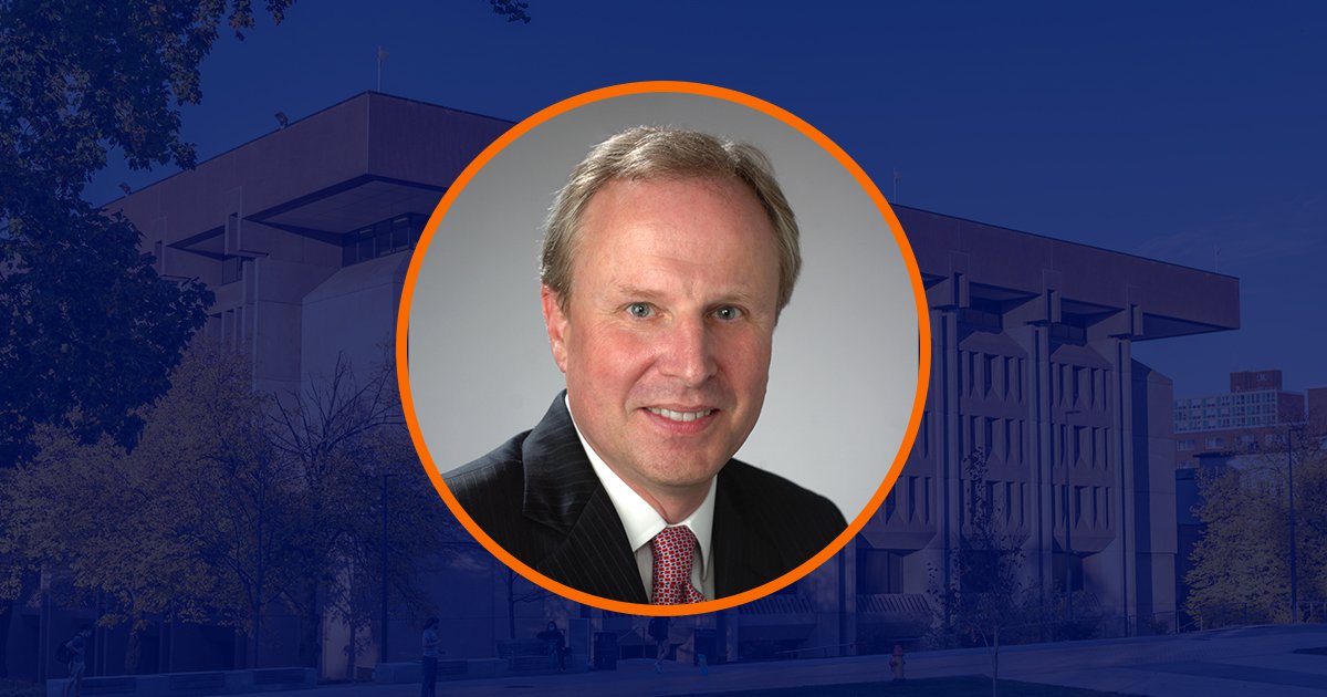 Circular portrait of Dean David Seaman with orange outline over dark blue overlaid image of Bird Library