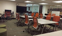 classroom with tables and chairs, large screen tv
