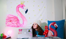 girl laying on dorm room bed, working on laptop with pink flamingo picture on wall and stuffed flamingo on bed