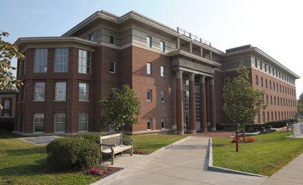 multi-floor brick building with columns in front and section on side shaped like polygon