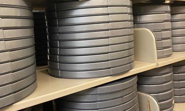Rows of circular gray film cans stacked on shelves
