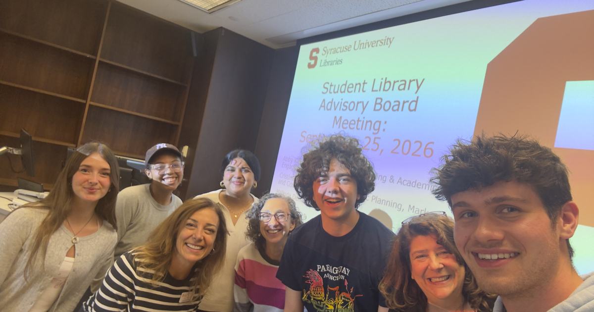 group of students and staff taking self with screen behind