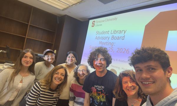group of students and staff taking self with screen behind
