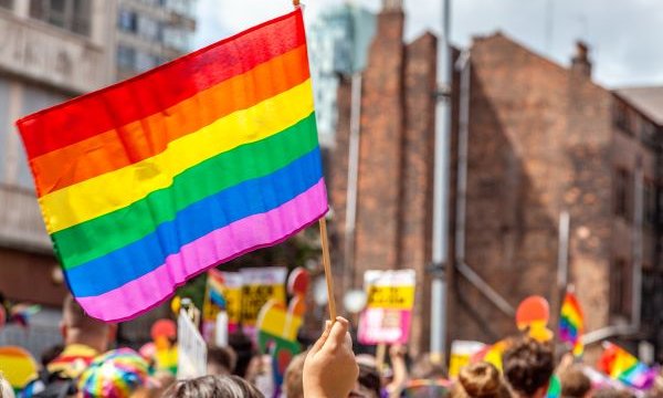 rainbow flag held up above crowd of heads