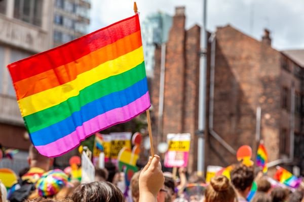 rainbow flag held up above crowd of heads