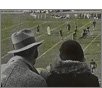 backside of man wearing hat and woman watching football game