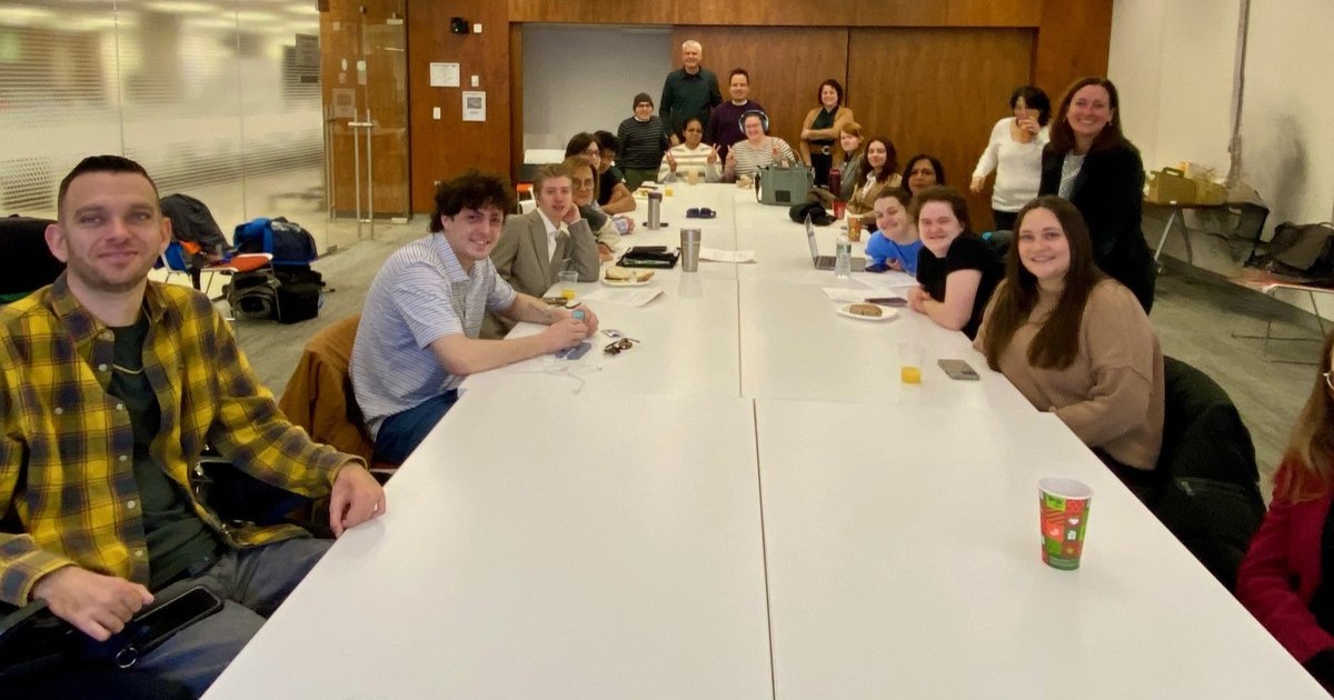 people sitting and standing around large conference room table