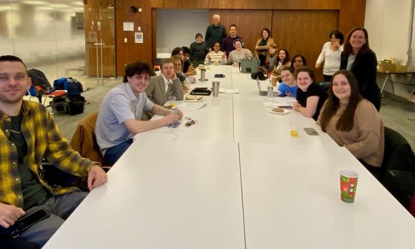 people sitting and standing around large conference room table