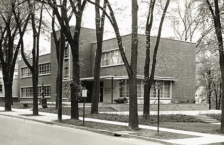 brick building behind row of trees