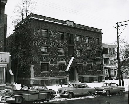 multi level brick building with flat front, cars parked in front