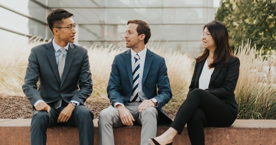 three PhD students sit in front of Whitman building