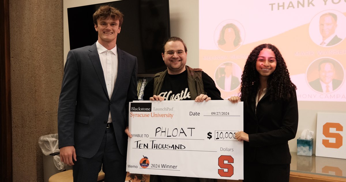 three people standing holding giant check