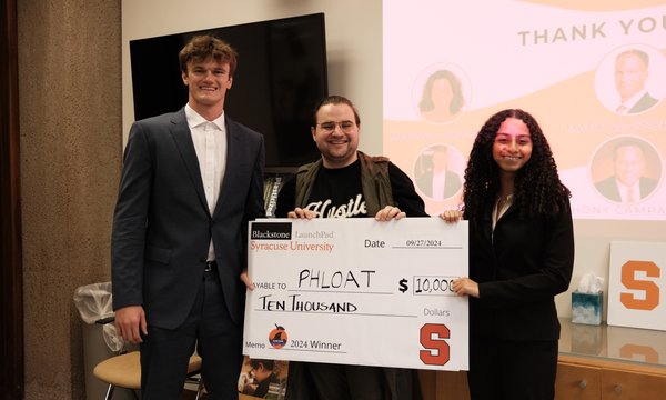 three people standing holding giant check