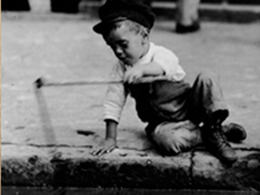 black and white photo of little boy wearing hat and holding stick