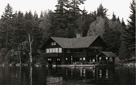 brown wooden building with lake in front and trees around it