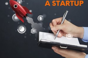 hand writing in notebook with rocket ship taking off next to it