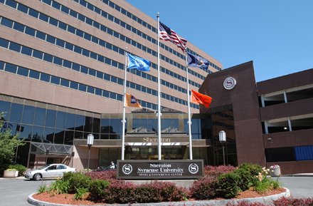 brick hotel with name in front and flags as part of circular drive