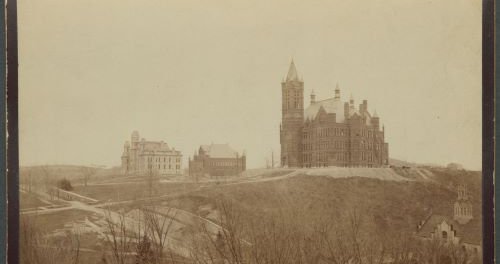 black and white photo of three buildings on hill
