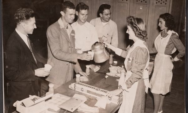 b&w male students lined up around table being served by female students