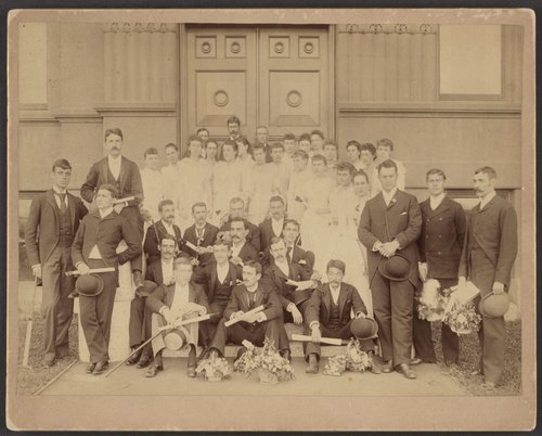 Group photo of men in suits and women in white dresses