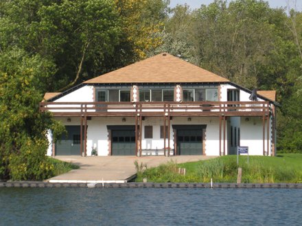 two story boathouse with balcony, three garages; driveway in front of water