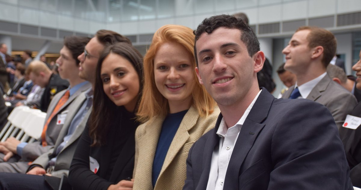 three students in professional attires smiling at the camera