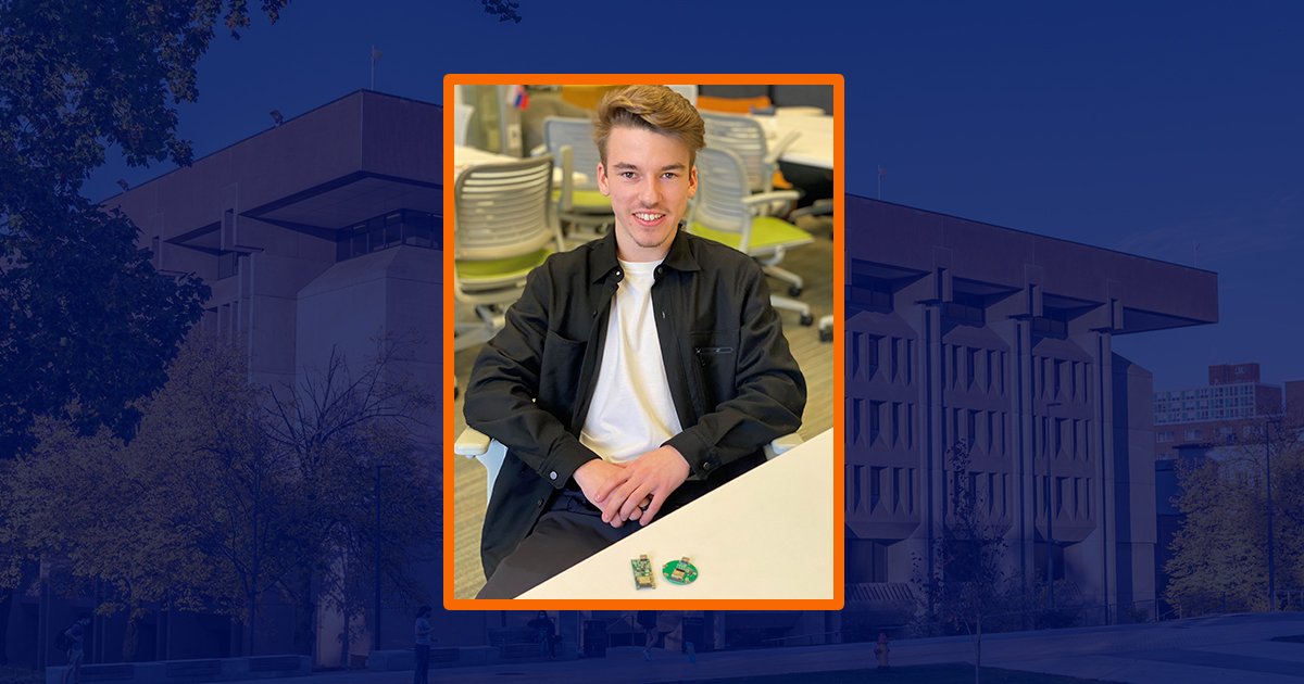 student wearing white shirt and black jacket sitting at table with small item on table