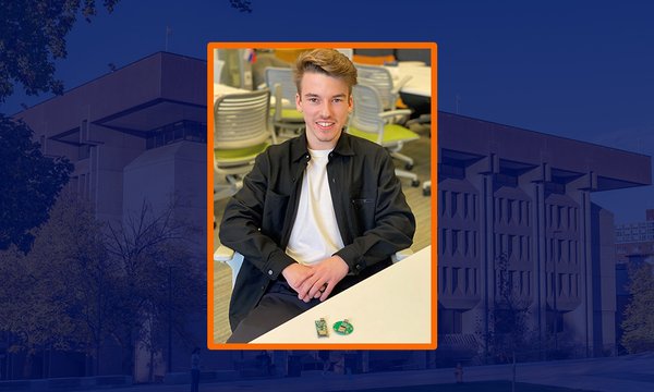 student wearing white shirt and black jacket sitting at table with small item on table