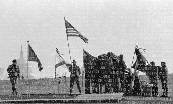 Capitol Building in background with people dressed in military uniforms at memorial