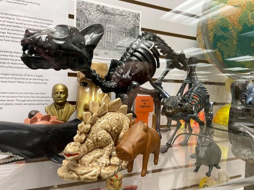 close up of items on display including lizard figurine, tiny bust of man, small animal skeletons, globe