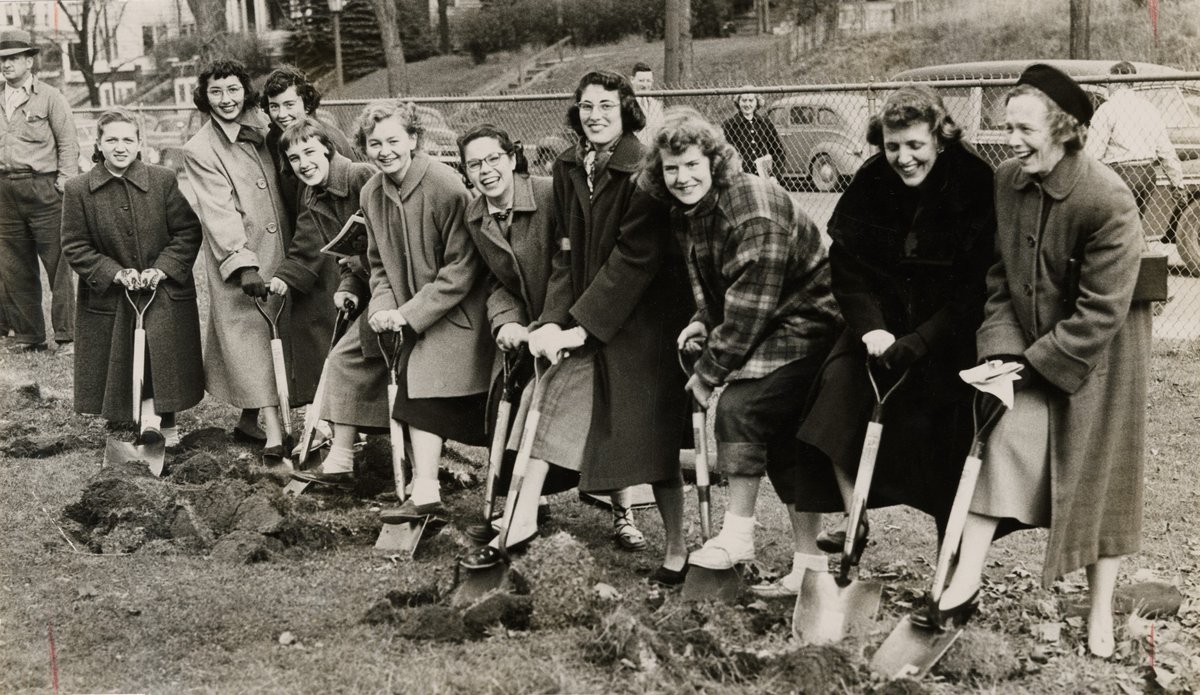 black and white of 10 women in row with shovels digging into dirt